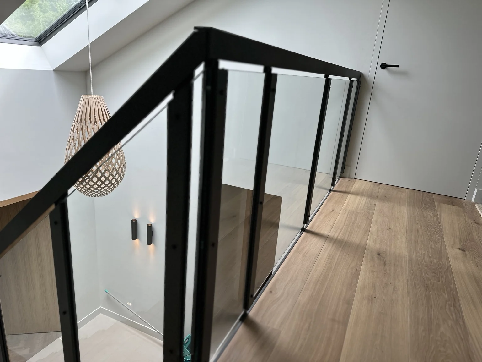 Balustrade met zwarte staanders en glazen panelen langs een vide