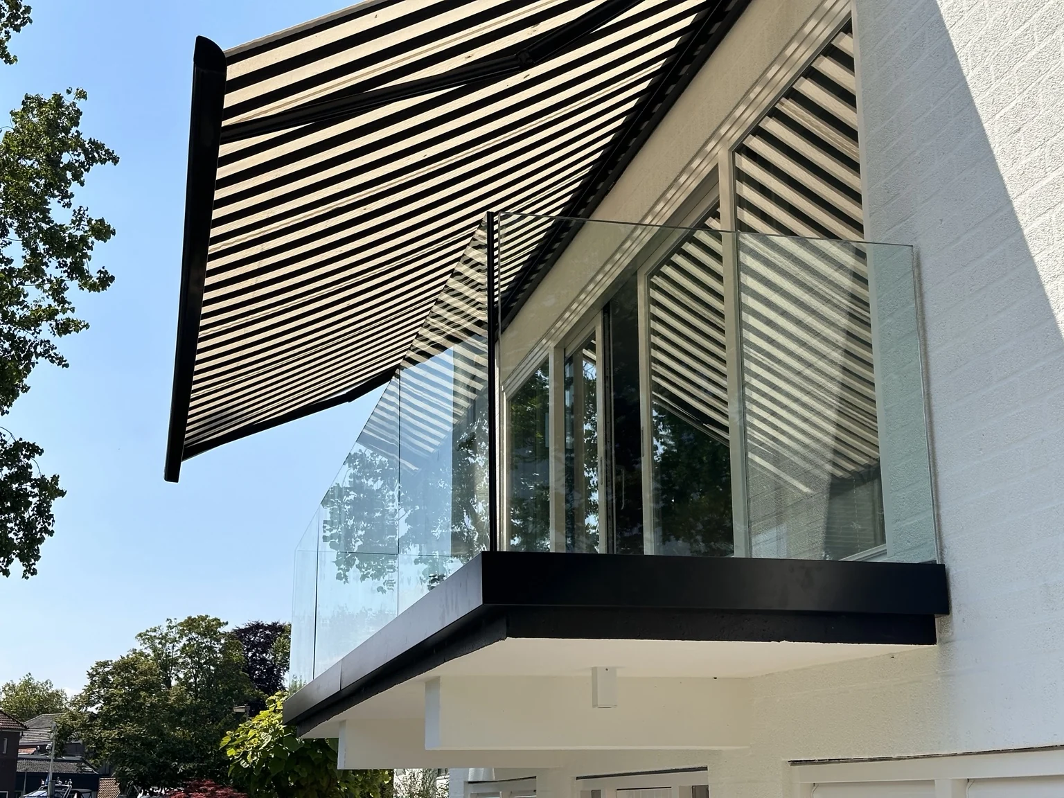 Glazen balkonbalustrade onder een zonnescherm