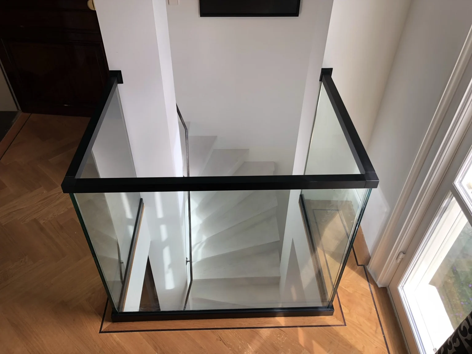 Glazen balustrade met zwarte bovenregel rond een trapgat