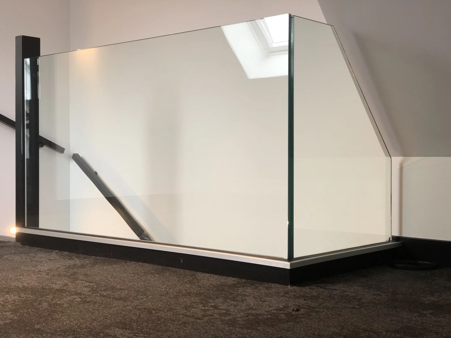 Glazen balustrade met een schuine bovenzijde rond een trapgat
