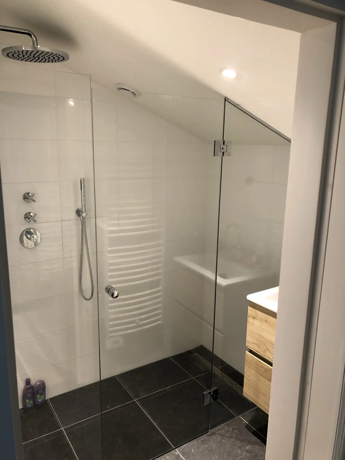 Glazen douchewand en deur onder een schuin plafond