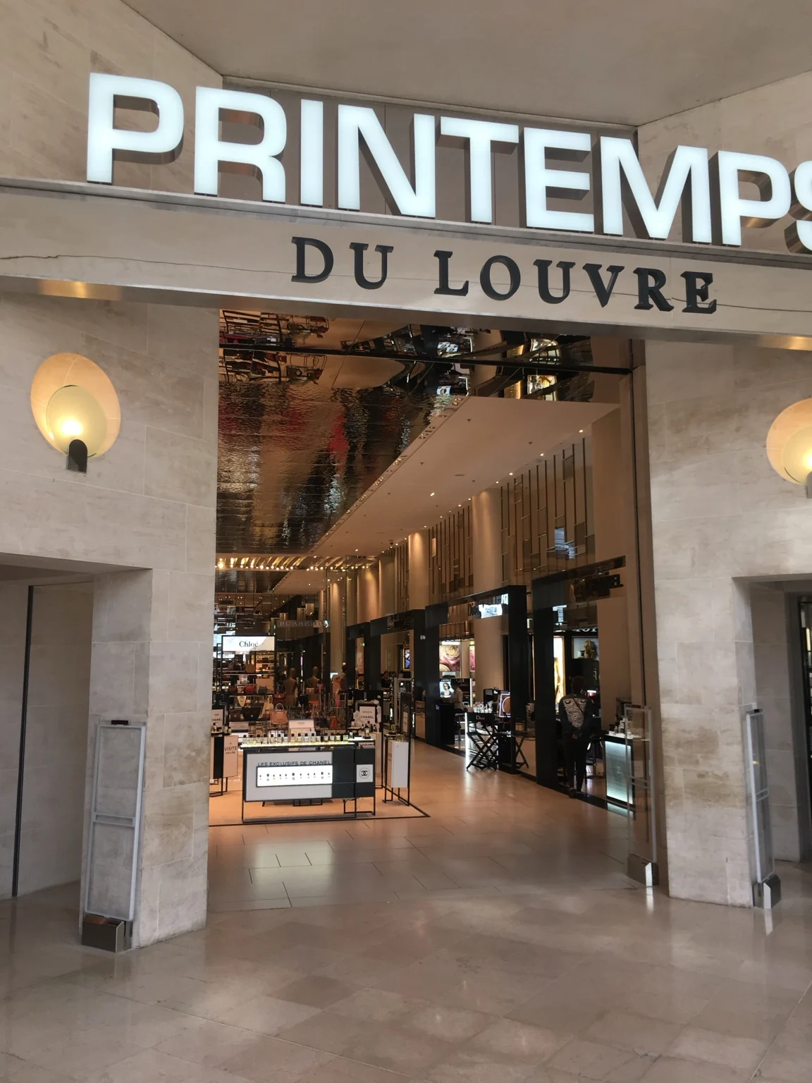 Entree van Printemps du Louvre met reflecterende vlakken in het interieur